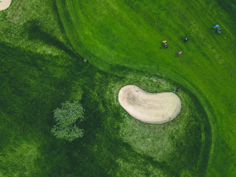 Golf basics for beginners: Aerial shot of a golf course bunker and green fairways.