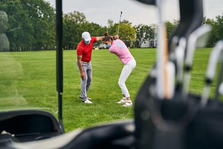 Golf Swing lessons in Phuket: Golf instructor guiding a student’s swing outdoors.