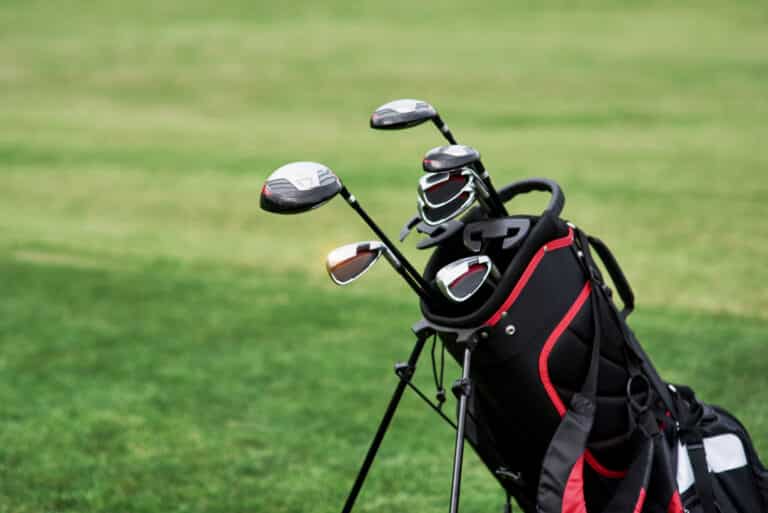Types of golf clubs: A golf bag filled with clubs on a green fairway.