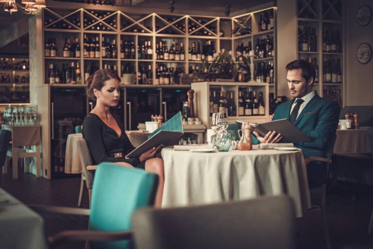 top restaurants in Laguna Phuket: A stylish couple in a fine dining restaurant reviewing the menu.