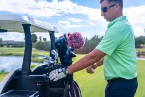 Golf gear trends in Phuket: A golfer in a green polo shirt selecting a club from his golf bag on a buggy.