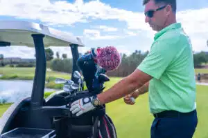 Golf gear trends in Phuket: A golfer in a green polo shirt selecting a club from his golf bag on a buggy.
