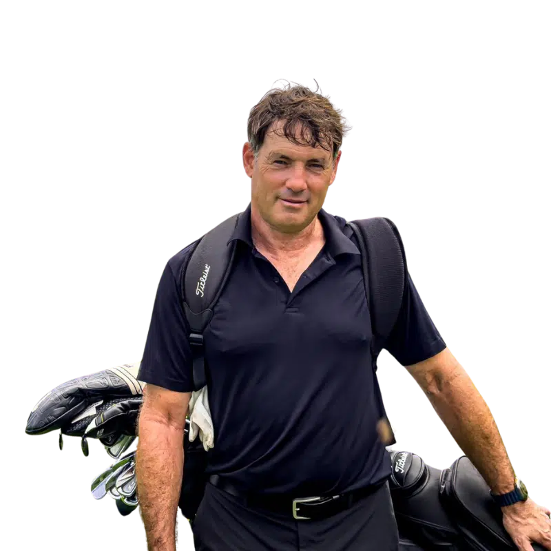 Lessons 3 Phuket golf lessons: Golf coach in Laguna Phuket: Jeff Craig standing confidently with a golf bag and clubs, wearing a black polo shirt, against a transparent background.