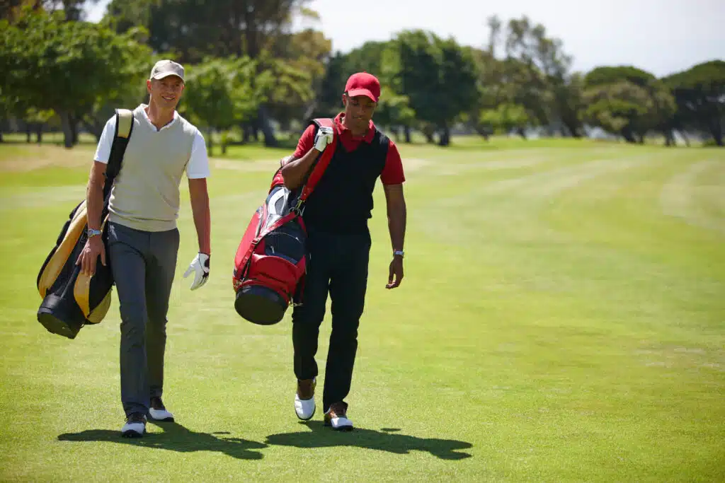 Best month for playing golf in Phuket: Two golfers walking together on the fairway carrying their golf bags.