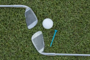 iron play: Golf ball, irons, and tee on the grass.