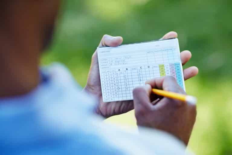 Golf Handicap for Beginners – How It Works & Improvement Tips 1 Golf handicap for beginners: Golfer recording scores on a golf scorecard