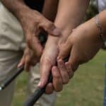 Phuket golf grip lessons: Close-up of a golf instructor adjusting a student's grip on a golf club.