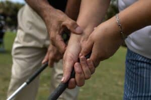 Phuket golf grip lessons: Close-up of a golf instructor adjusting a student's grip on a golf club.