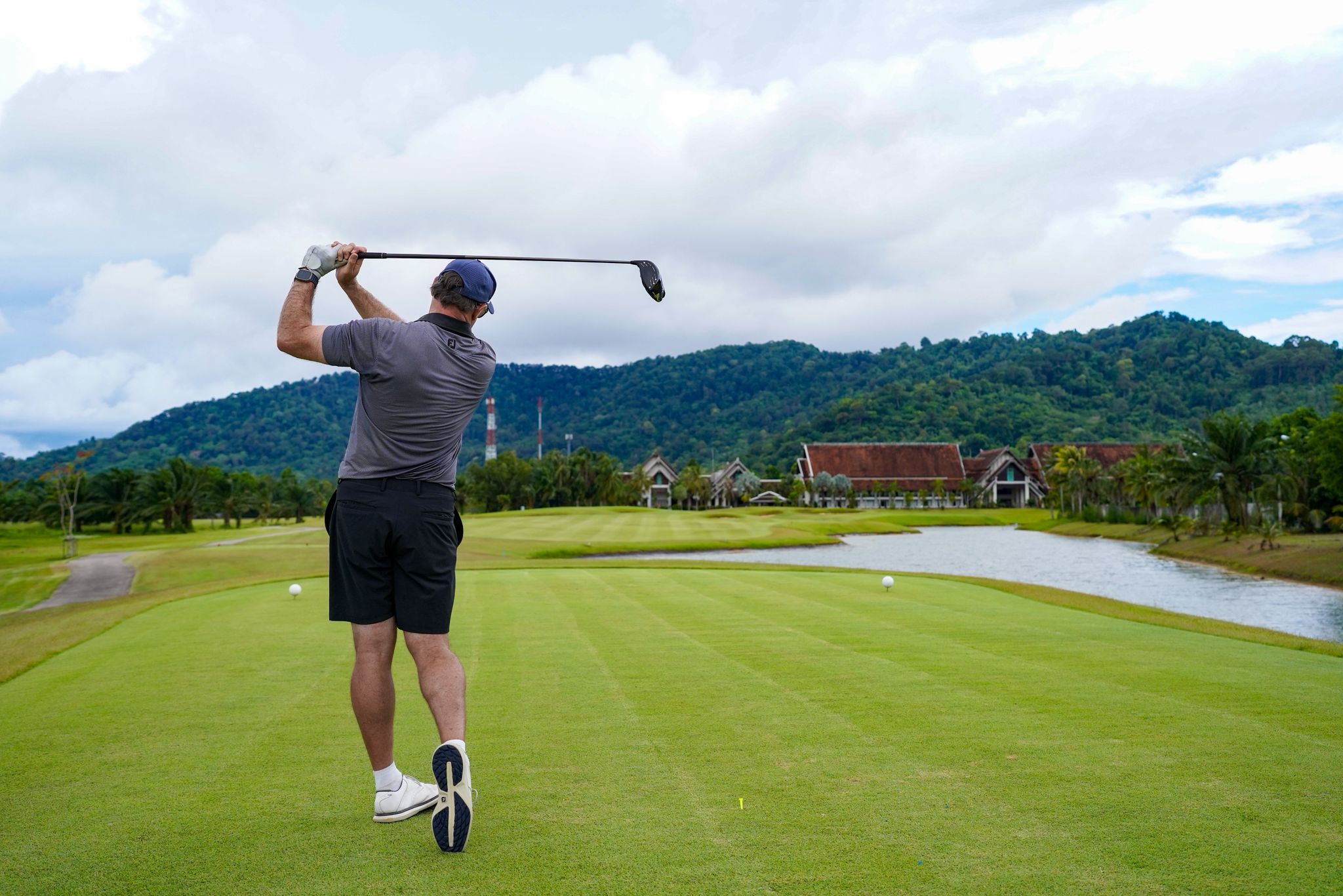 About 1 A stunning aerial view of Laguna Golf Course in Phuket, showcasing lush greens, a tranquil lake, and residential villas by the seaside.