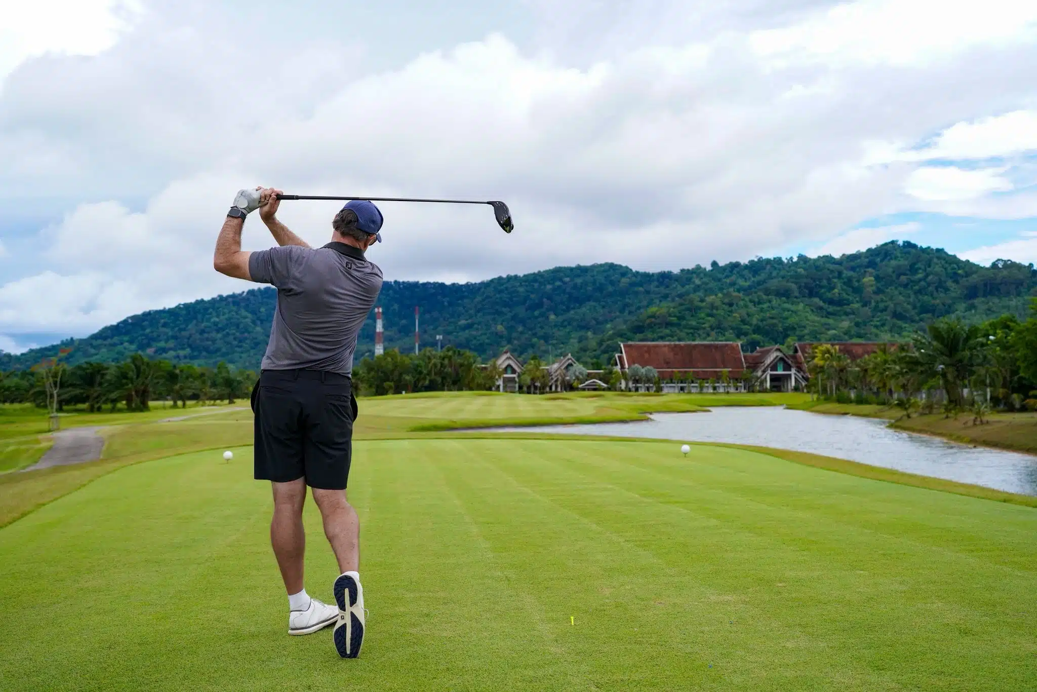 A stunning aerial view of Laguna Golf Course in Phuket, showcasing lush greens, a tranquil lake, and residential villas by the seaside.